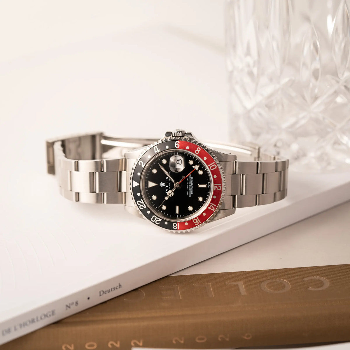 Rolex GMT-Master II der Referenz 16710  2000 mit  schwarz-roter Coke-Lünette und dem für das Jahr 2000 typische "Swiss Only" - Zifferblatt liegt seitlich auf der seitlichen Gehäuseflanke