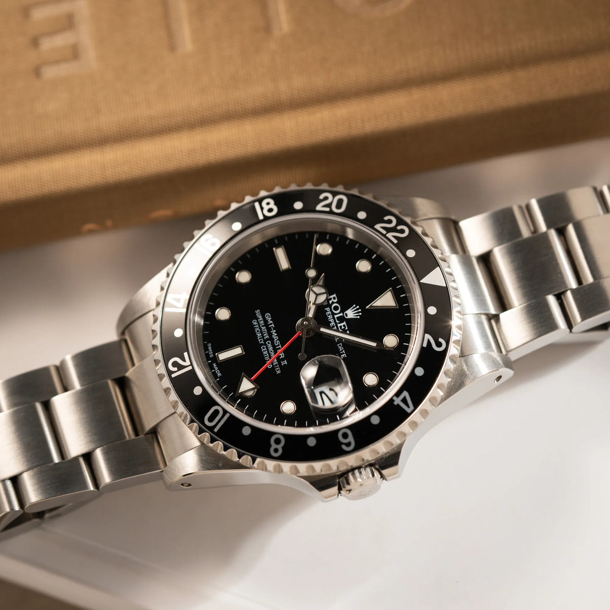 Produktfotografie der flach auf dem Uhrenarmband liegenden Rolex GMT-Master II 16710  aus 2001 mit schwarzem Aluminium-Lünetten-Inlay in einem neuwertigen Zustand 