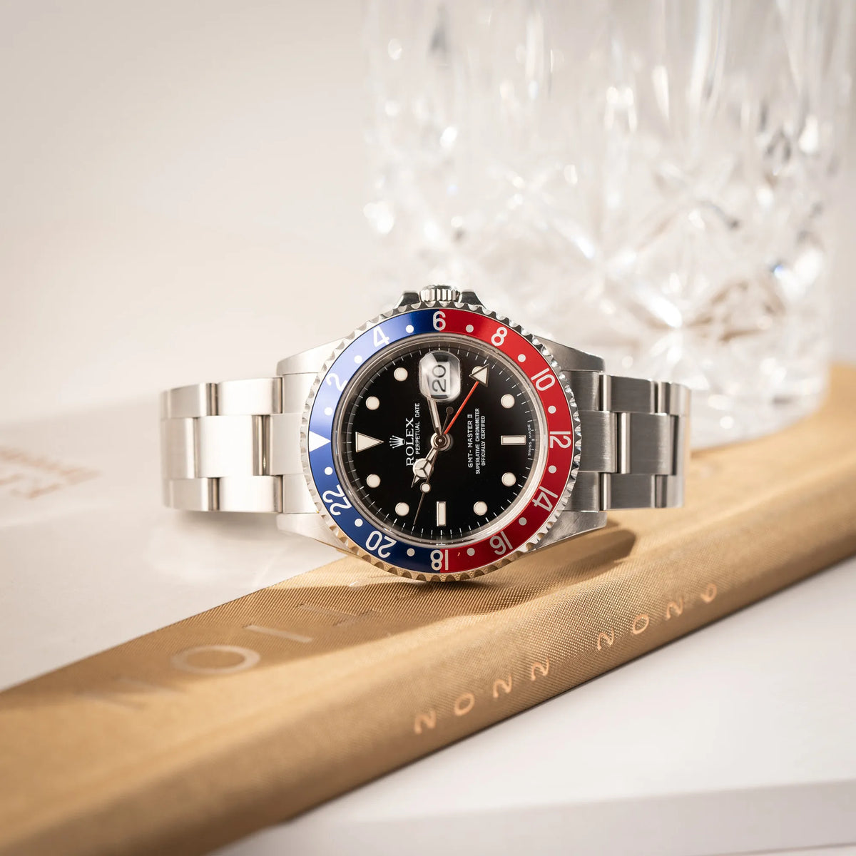 Rolex GMT-Master II der Referenz 16710 mit der blau-roten Pepsi Lünette aus Aluminium mit kräftigen Farben liegt auf einem Uhrenbuch