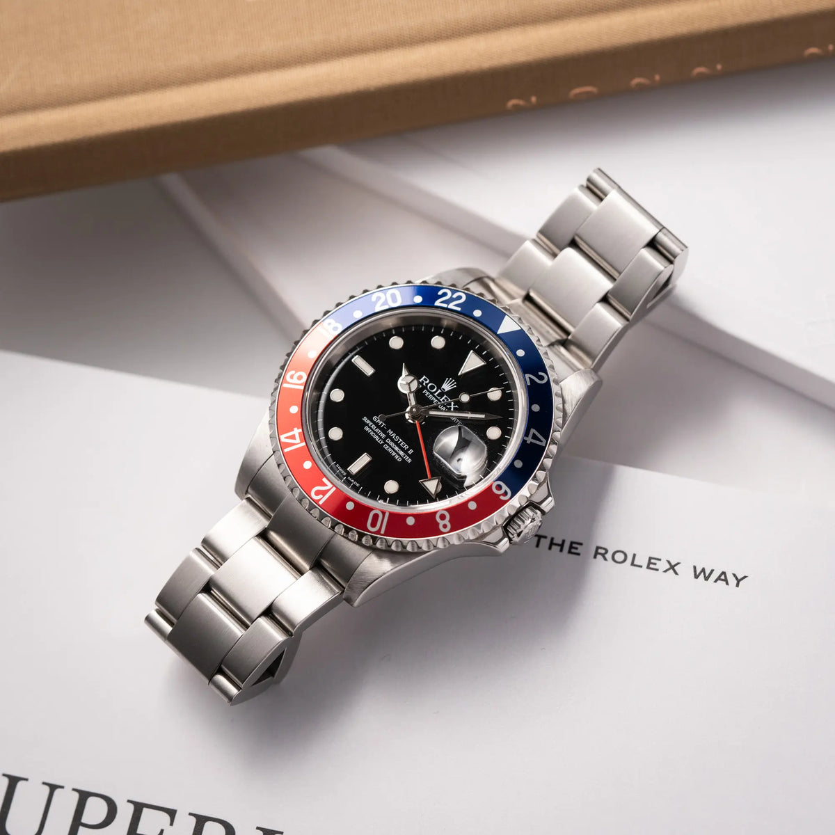 Rolex GMT-Master II der Referenz 16710 mit der blau-roten Pepsi Lünette aus Aluminium mit kräftigen Farben liegt flach auf einem Rolex-Magazin