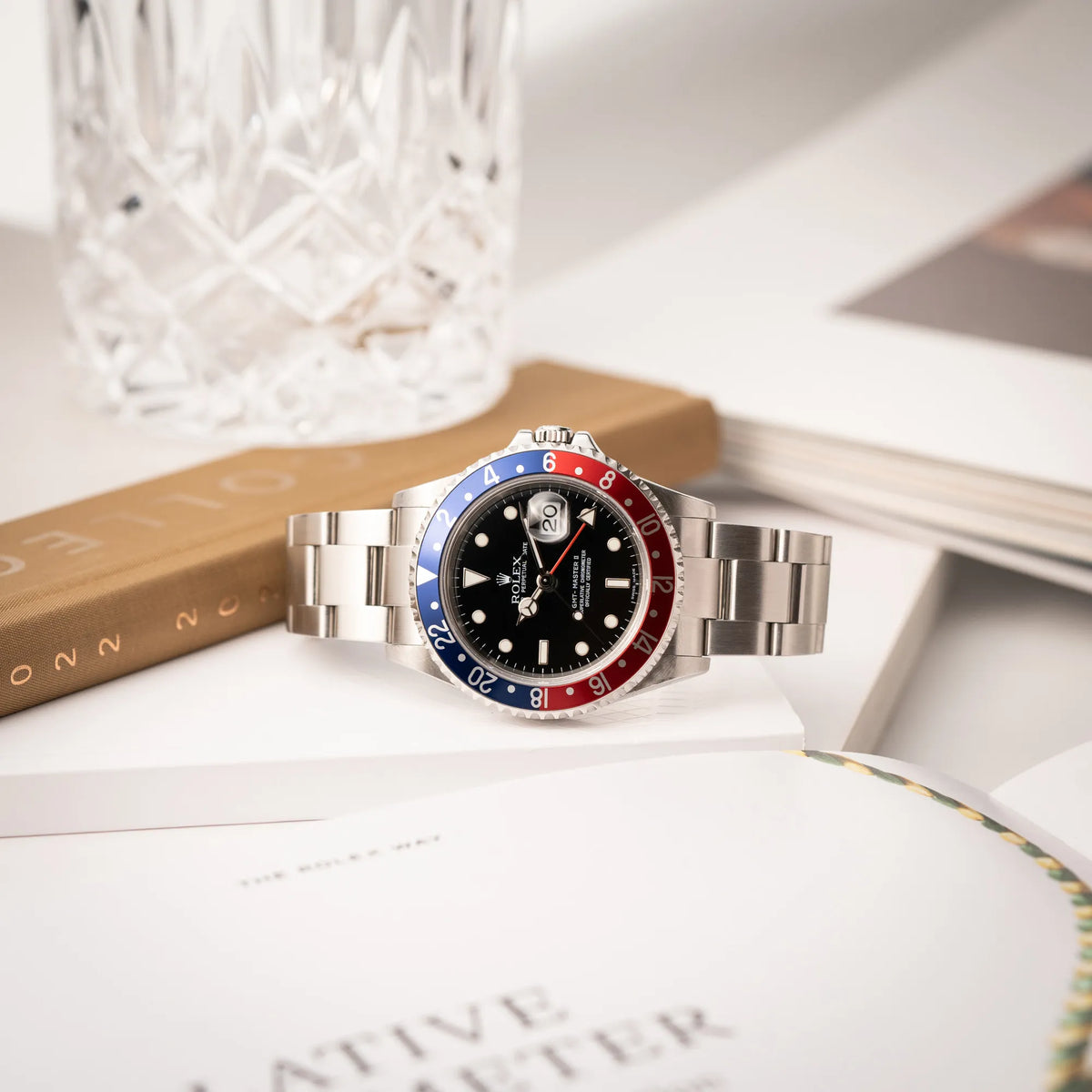 Produktfotografie der seitlich auf dem Uhrengehäuse liegenden Rolex GMT-Master II der Referenz 16710 mit der blau-roten Pepsi Lünette aus Aluminium mit kräftigen Farben