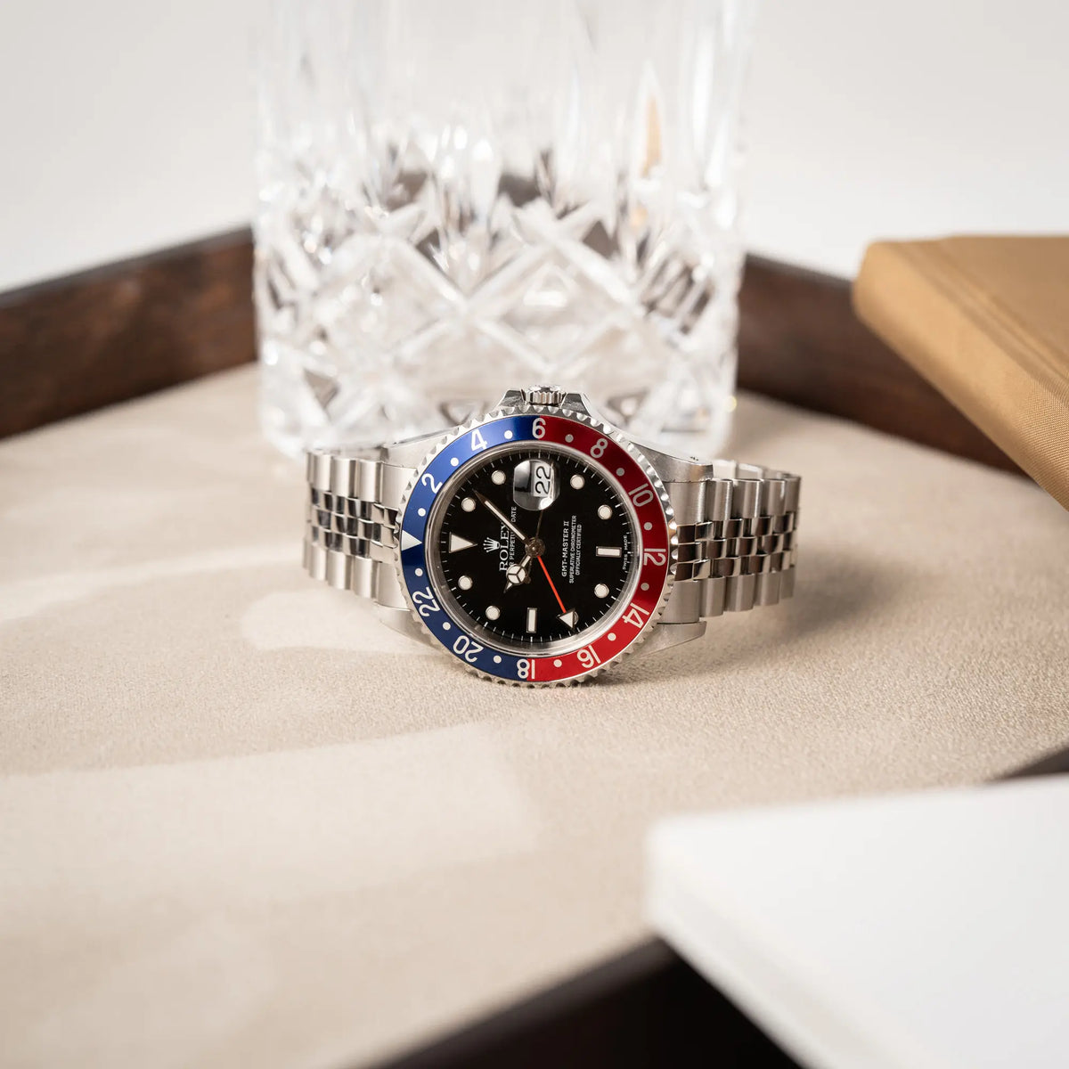 Produktfotografie der seitlich auf dem Uhrengehäuse liegenden Rolex GMT-Master II 16710 mit der blau-roten Pepsi-Lünette am Jubilee-Armband 