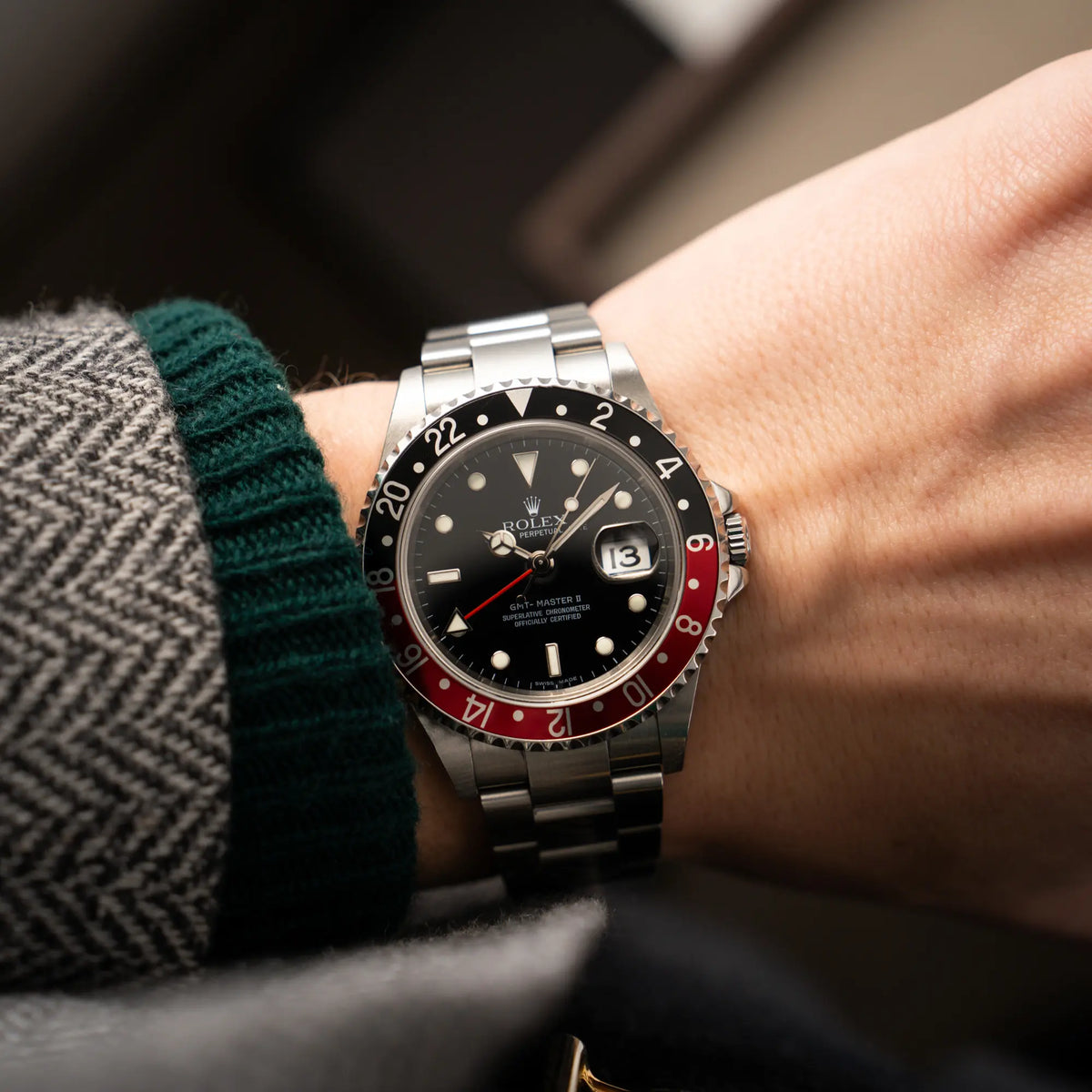 Mann trägt die Rolex GMT-Master II der Referenz 16710 mit der schwarz-roten "Coke"-Lünette aus 2007 mit dem "No-Hole"-Uhrengehäuse für einen Wristshot an seinem Handgelenk