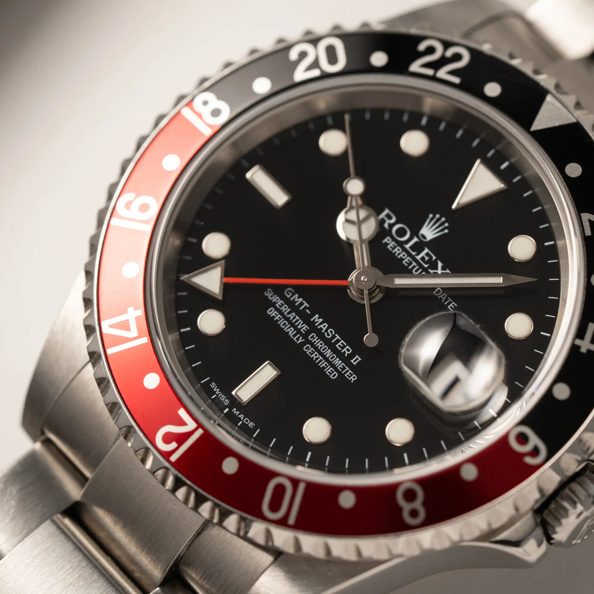 Makroaufnahme der Rolex GMT-Master II der Referenz 16710 mit der schwarz-roten "Coke"-Lünette aus 2007 mit dem "No-Hole"-Uhrengehäuse mit Fokus auf dem roten GMT-Zeiger