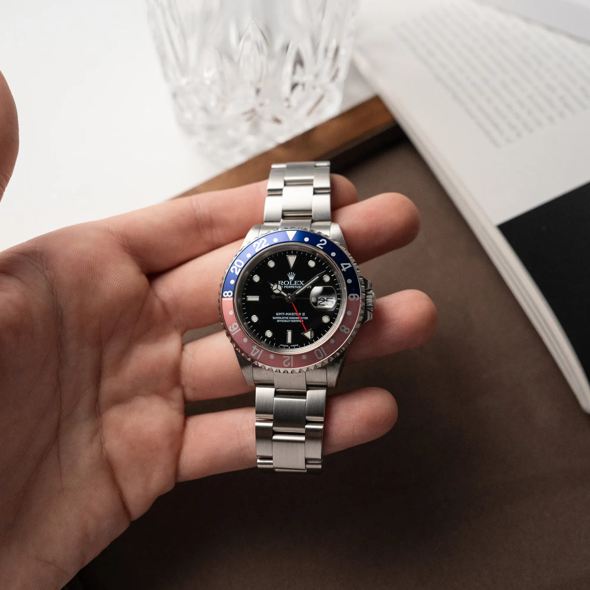Mann hält die Rolex GMT-Master 2 der Referenz 16710 mit der blau-roten Pepsi Lünette, die einen wunderschönen verblichenen Raspberry-Farbton in seiner Hand