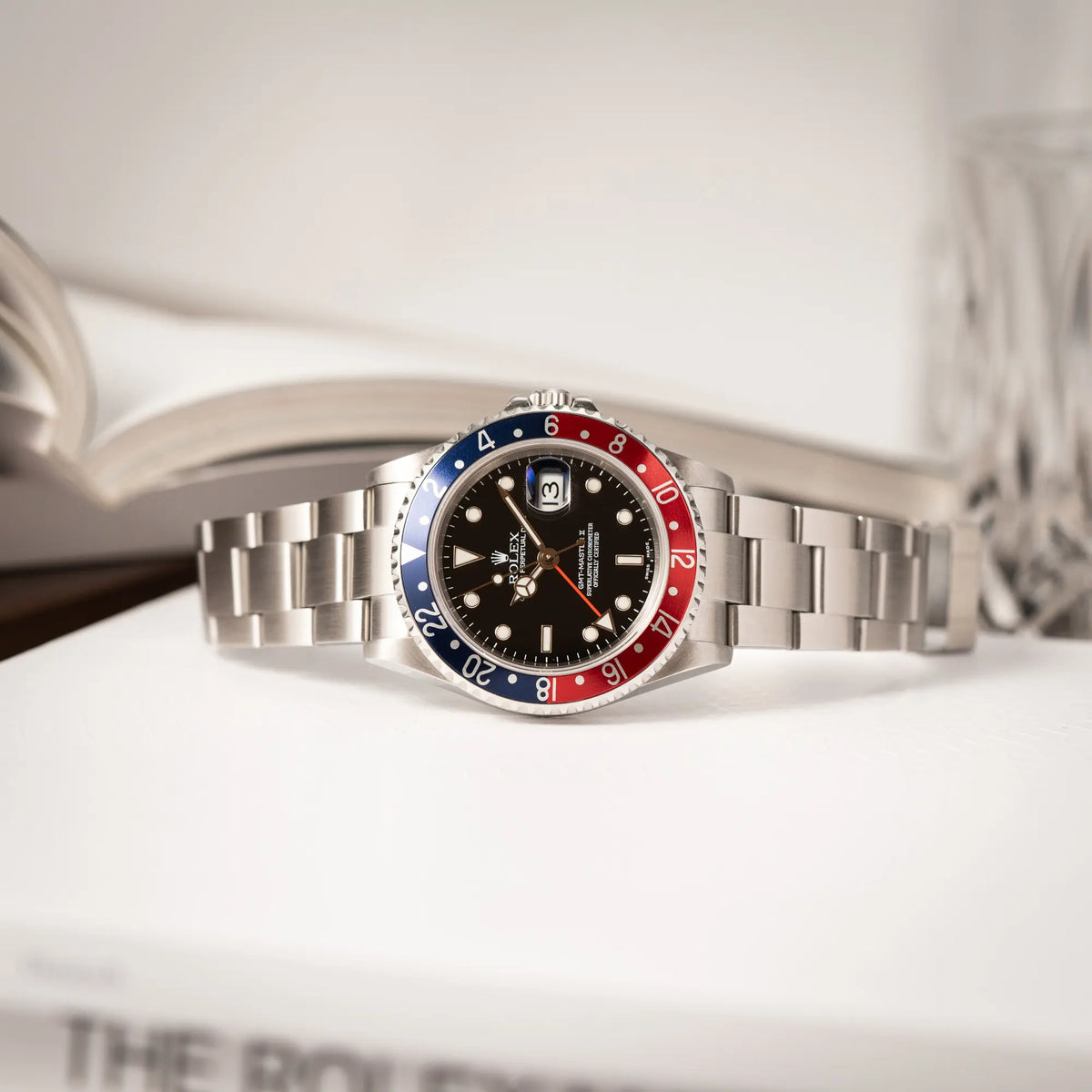 Rolex GMT-Master II Pepsi der Referenz 16710 mit der blau-roten Aluminium-Lünette liegt seitlich auf dem Uhrengehäuse