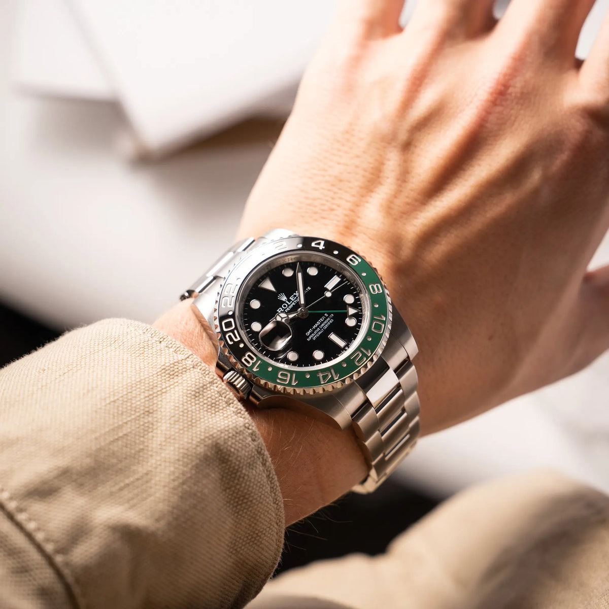 Mann trägt den Rolex GMT-Master II der Referenz 126720VTNR mit dem Nickname "Sprite" mit einer schwarz-grünen Keramik-Lünette am Oyster-Stahlband im neuwertigen Zustand, mit der Besonderheit der links liegenden Aufzugskrone, so dass Linkshänder die Uhr an der rechten Hand tragen können