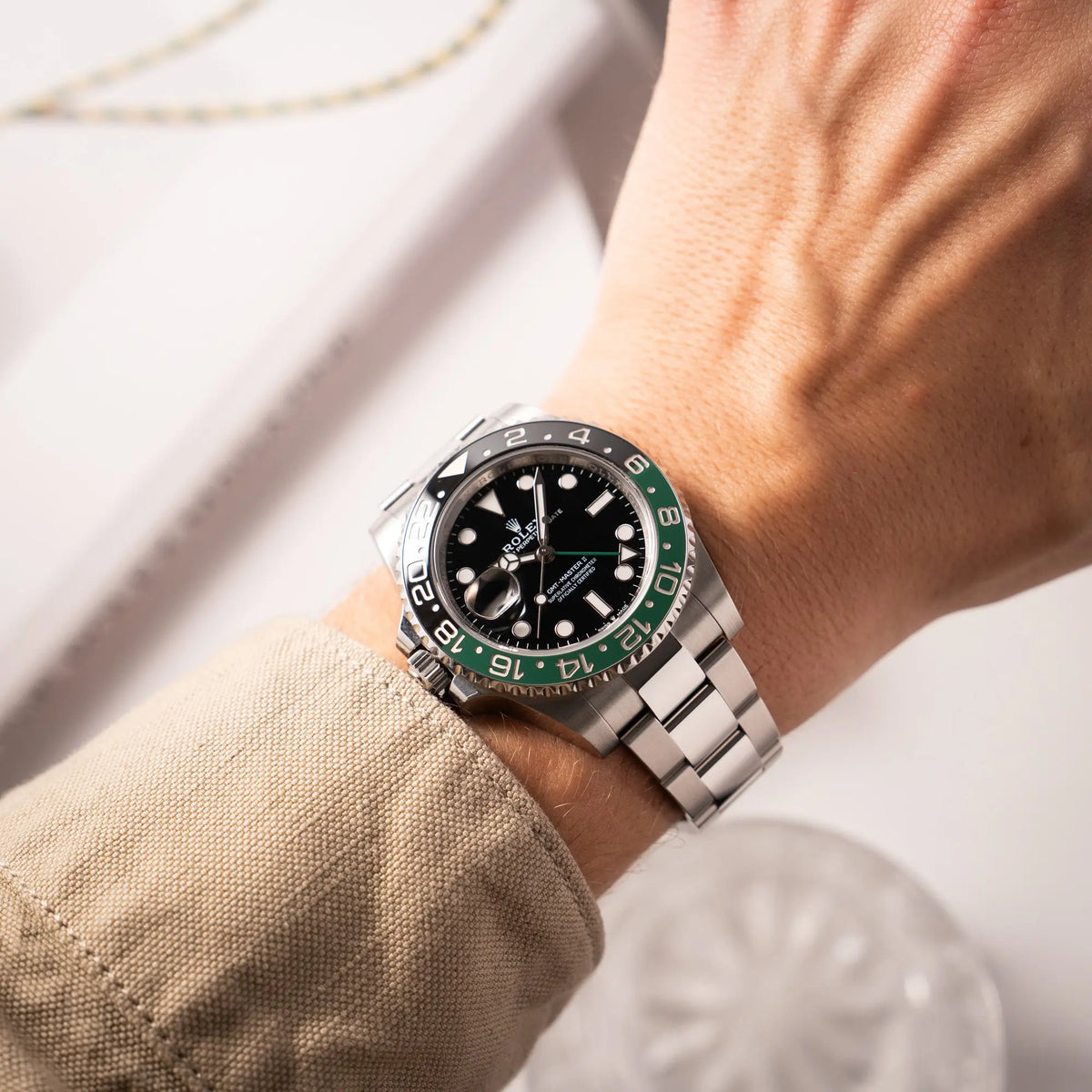 Wristshot an einem Männerhandgelenk von der Rolex GMT-Master II der Referenz 126720VTNR mit dem Nickname "Sprite" mit einer schwarz-grünen Keramik-Lünette am Oyster-Stahlband im neuwertigen Zustand, mit der Besonderheit der links liegenden Aufzugskrone, so dass Linkshänder die Uhr an der rechten Hand tragen können