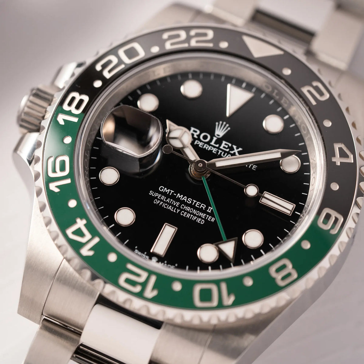 Detailaufnahme zeigt den Uhrenkopf der Rolex GMT-Master II der Referenz 126720VTNR mit dem Nickname "Sprite" mit einer schwarz-grünen Keramik-Lünette am Oyster-Stahlband im neuwertigen Zustand, mit der Besonderheit der links liegenden Aufzugskrone, so dass Linkshänder die Uhr an der rechten Hand tragen können