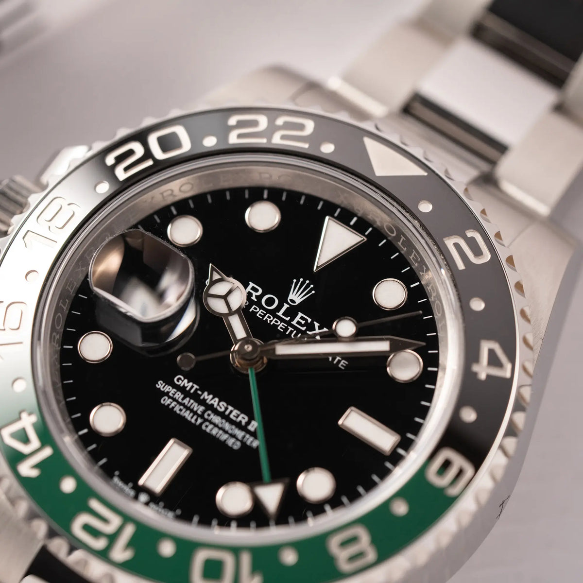Nahaufnahme der Rolex GMT-Master II der Referenz 126720VTNR mit dem Nickname "Sprite" mit einer schwarz-grünen Keramik-Lünette am Oyster-Stahlband im neuwertigen Zustand, mit der Besonderheit der links liegenden Aufzugskrone, so dass Linkshänder die Uhr an der rechten Hand tragen können