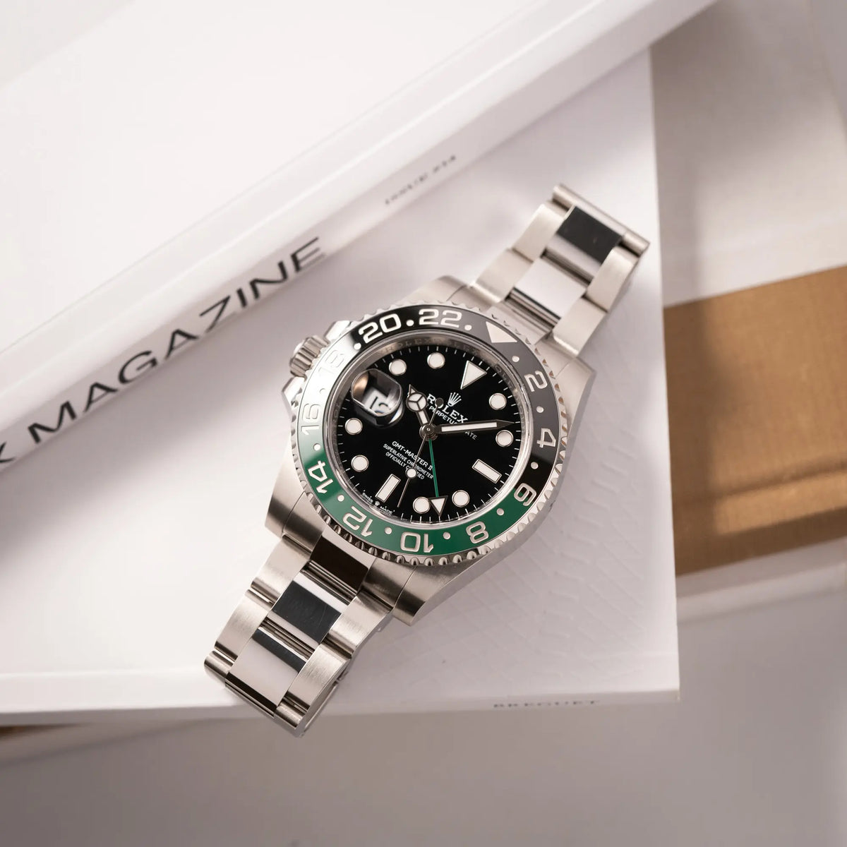 Produktfotografie der Rolex GMT-Master II der Referenz 126720VTNR mit dem Nickname "Sprite" mit einer schwarz-grünen Keramik-Lünette am Oyster-Stahlband im neuwertigen Zustand, mit der Besonderheit der links liegenden Aufzugskrone, so dass Linkshänder die Uhr an der rechten Hand tragen können