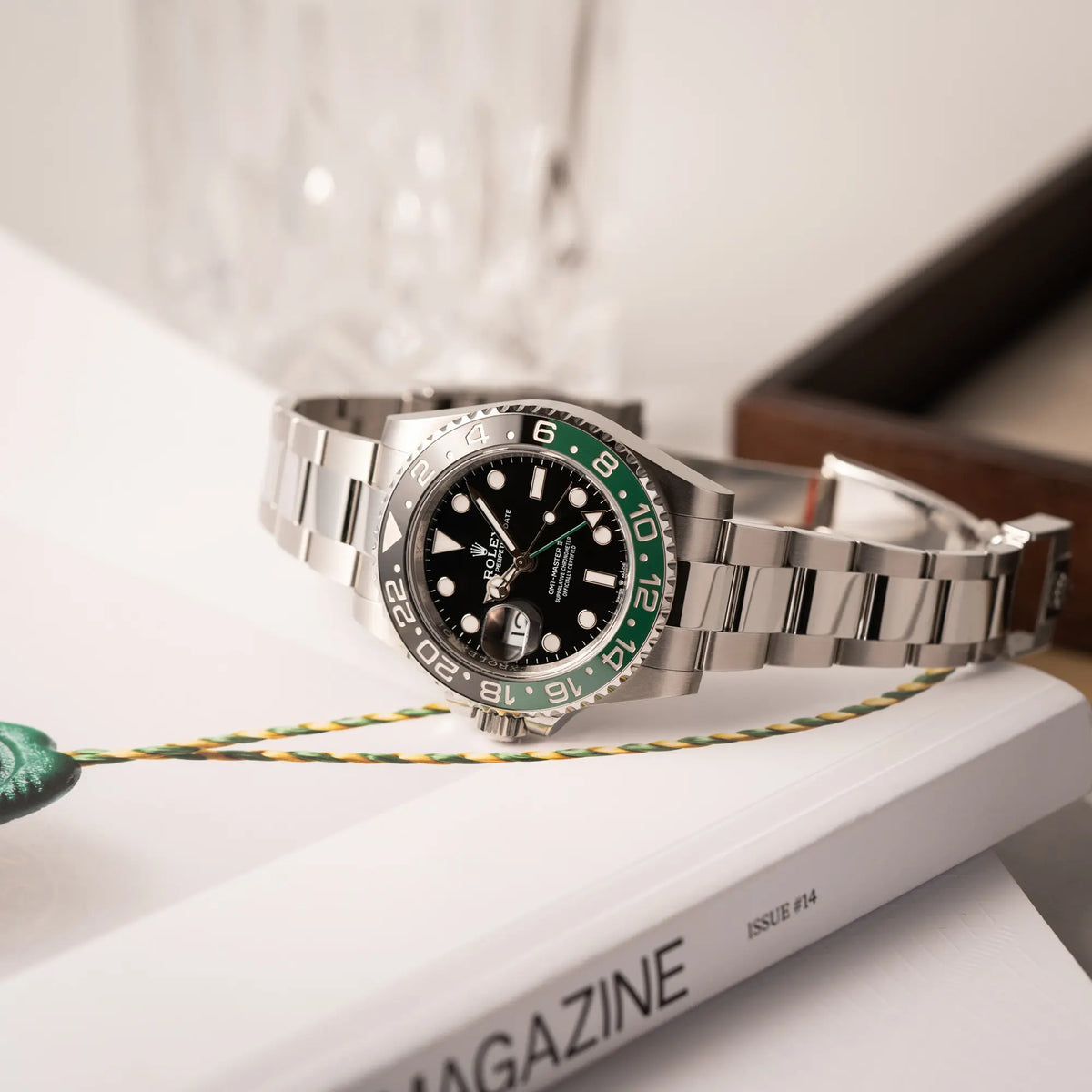 Produktfotografie der Rolex GMT-Master II der Referenz 126720VTNR mit dem Nickname "Sprite" mit einer schwarz-grünen Keramik-Lünette am Oyster-Stahlband im neuwertigen Zustand, mit der Besonderheit der links liegenden Aufzugskrone, so dass Linkshänder die Uhr an der rechten Hand tragen können