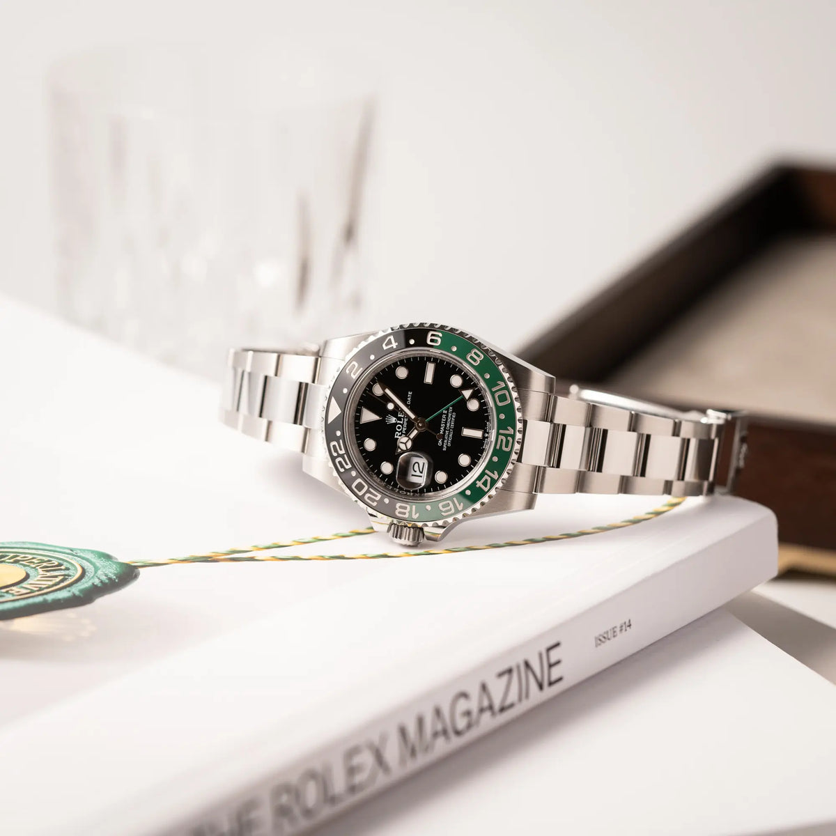 Rolex GMT-Master II der Referenz 126720VTNR mit dem Nickname "Sprite" mit einer schwarz-grünen Keramik-Lünette am Oyster-Stahlband im neuwertigen Zustand, mit der Besonderheit der links liegenden Aufzugskrone, so dass Linkshänder die Uhr an der rechten Hand tragen können, liegt seitlich auf einem Rolex Magazin
