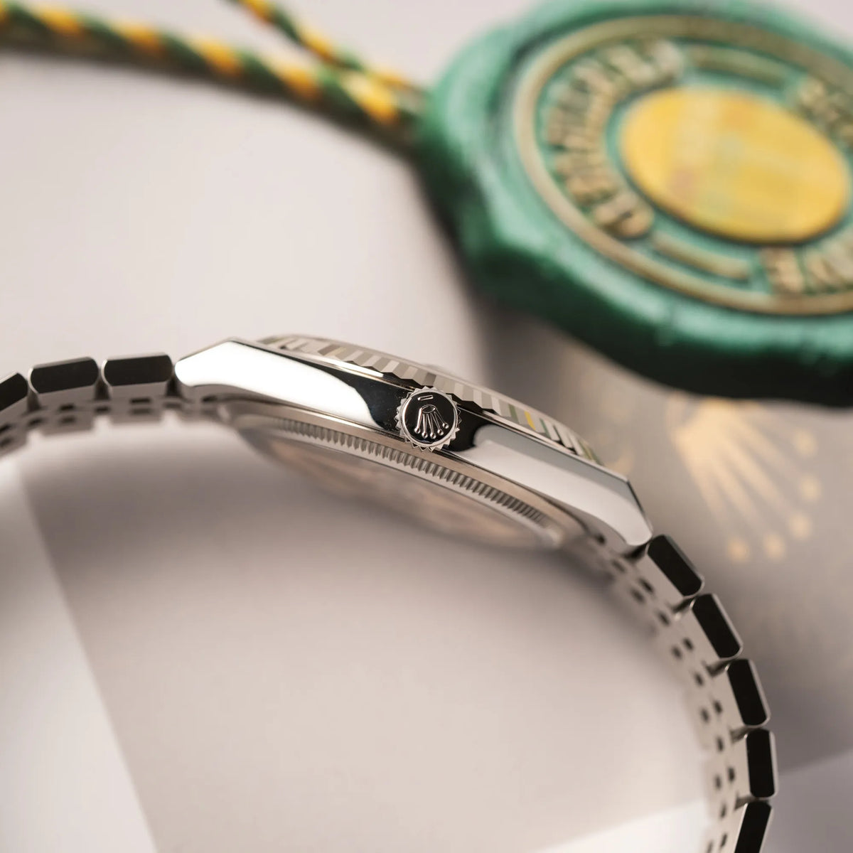 Seitliche Gehäuseflanke mit Blick auf die Aufzugskrone der Rolex Land-Dweller 40 der Referenz 127334 im neuwertigen Zustand mit dem weißen Zifferblatt in Waben-Struktur am neuen Flat-Jubilee-Armband