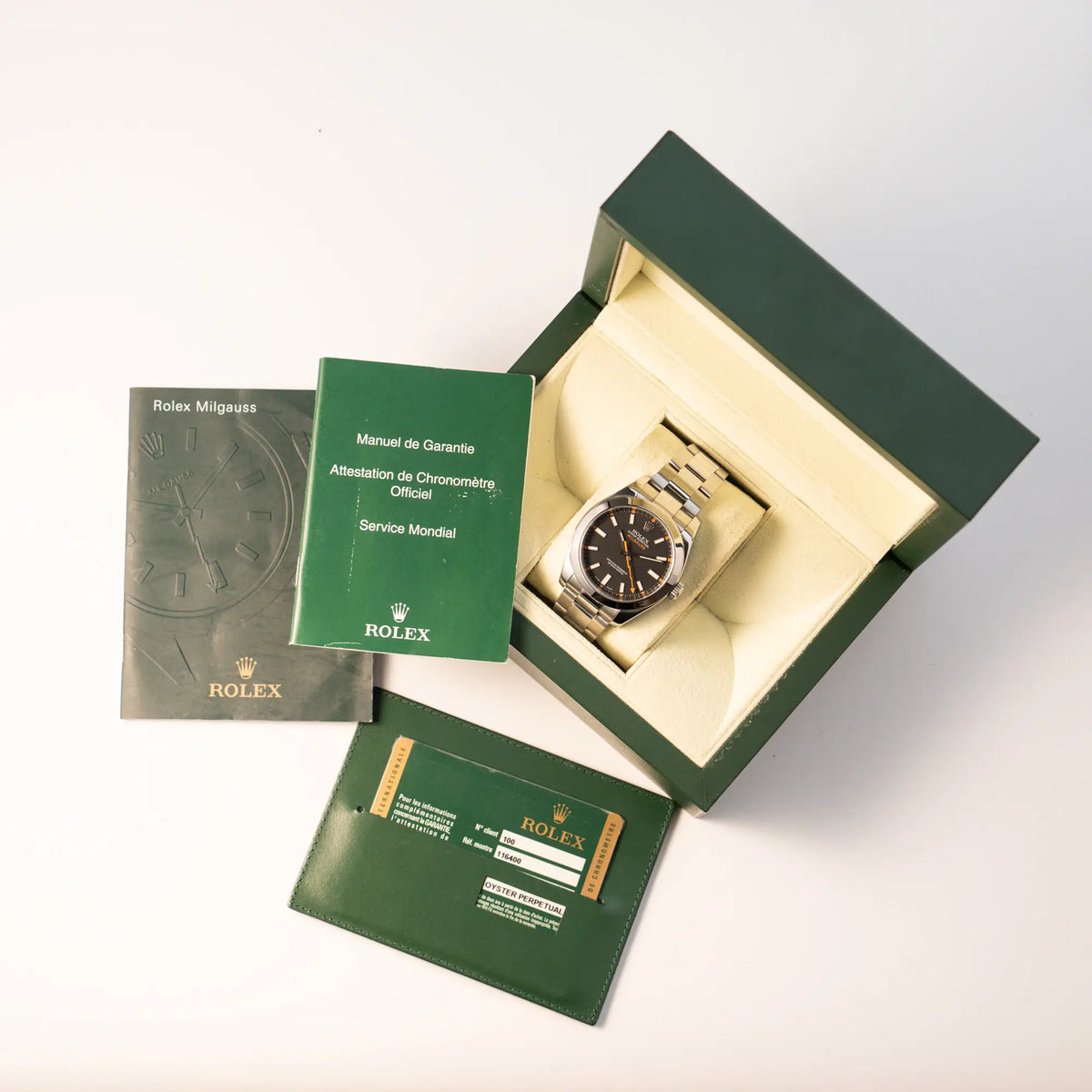 Rolex Milgauss der Referenz  116400 mit schwarzem Zifferblatt und orangen Akzenten zusammen mit dem Lieferumfang, bestehend aus Box, Papieren und Booklets