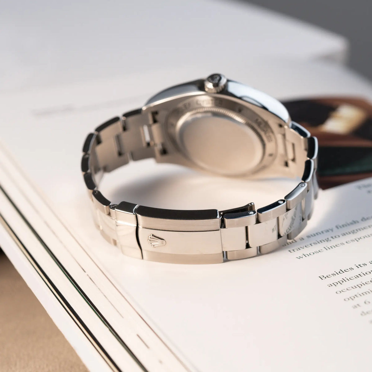 Produktfotografie der Rolex Milgauss der Referenz  116400 mit schwarzem Zifferblatt und orangen Akzenten zeigt die geschlossene Oyster-Faltschiesse