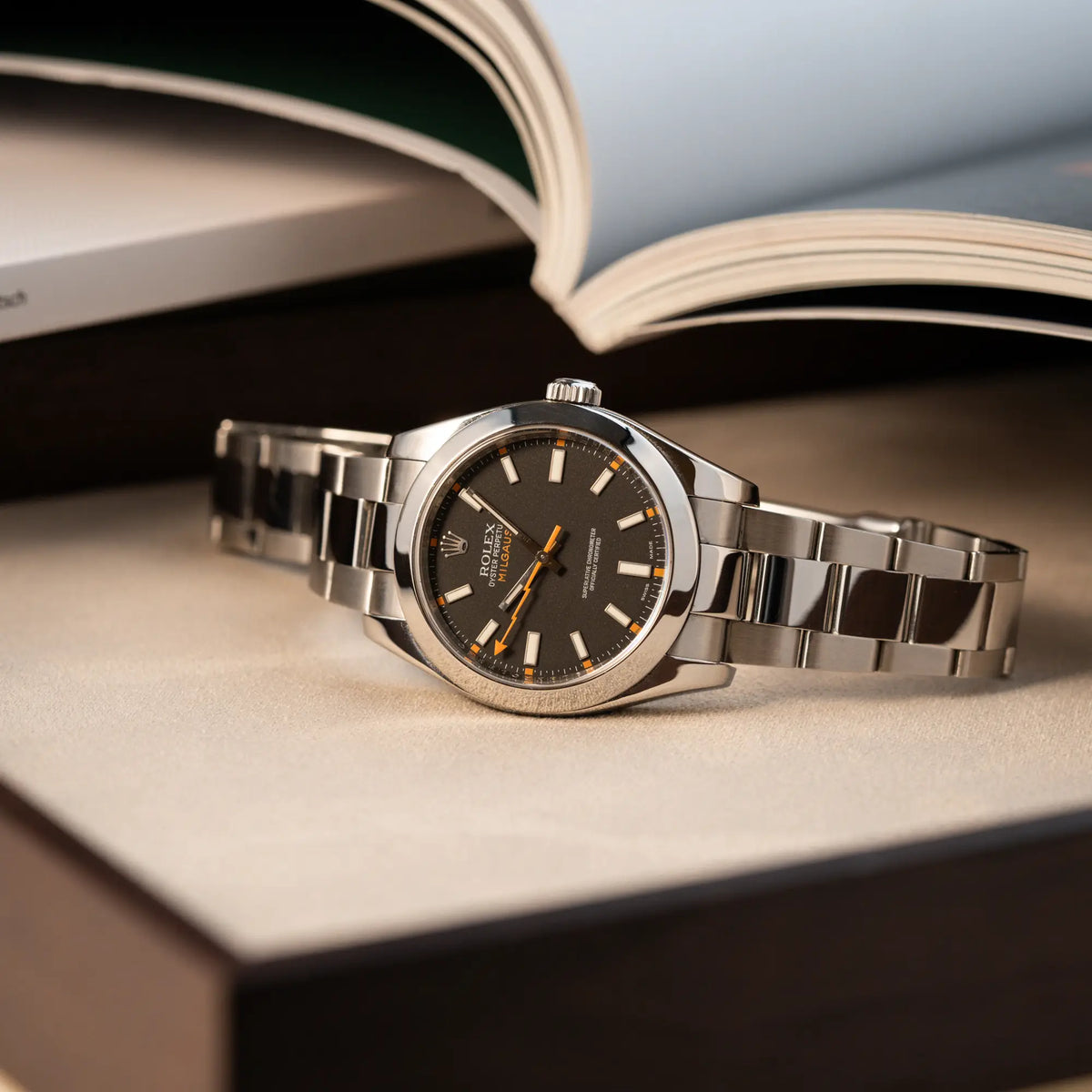 Produktfotgrafie der Rolex Milgauss der Referenz  116400 mit schwarzem Zifferblatt und orangen Akzenten auf Juwelierstablet