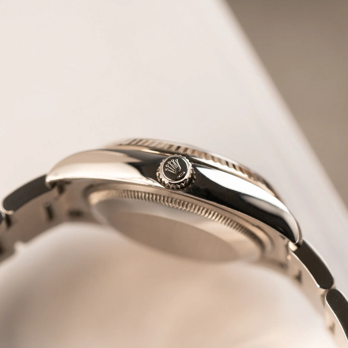 seitliche Gehäuseflanke der Rolex Oyster Perpetual Date 34 der Referenz 115234 mit schwarzem Zifferblatt und der geriffelten Weißgold-Lünette  mit Blick auf die Aufzugskrone 