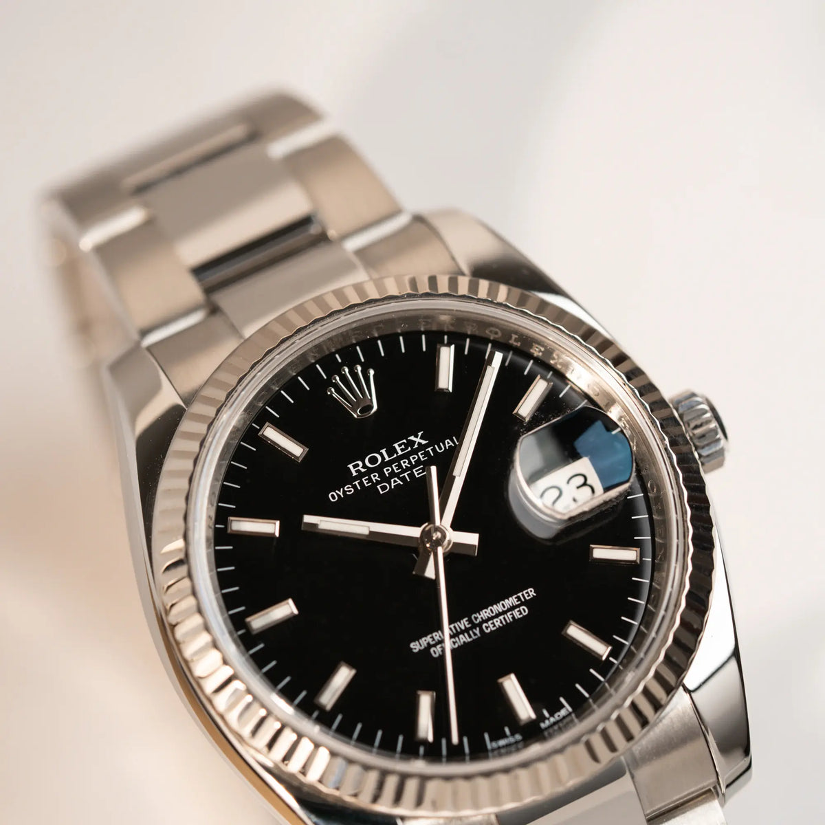 Detailaufnahme der Rolex Oyster Perpetual Date 34 der Referenz 115234 mit schwarzem Zifferblatt und der geriffelten Weißgold-Lünette 