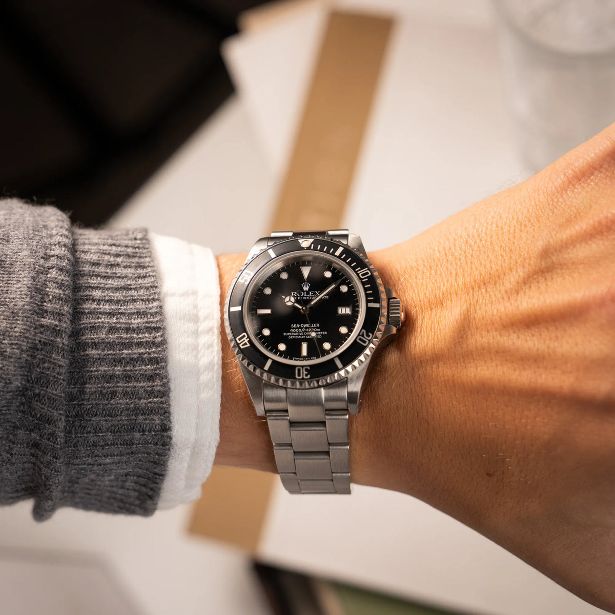 Mann trägt die Rolex Sea-Dweller 4000 der Referenz 16600 mit 40mm-Oyster-Gehäuse und schwarzer Aluminium-Lünetten-Inlay an seinem Handgelenk