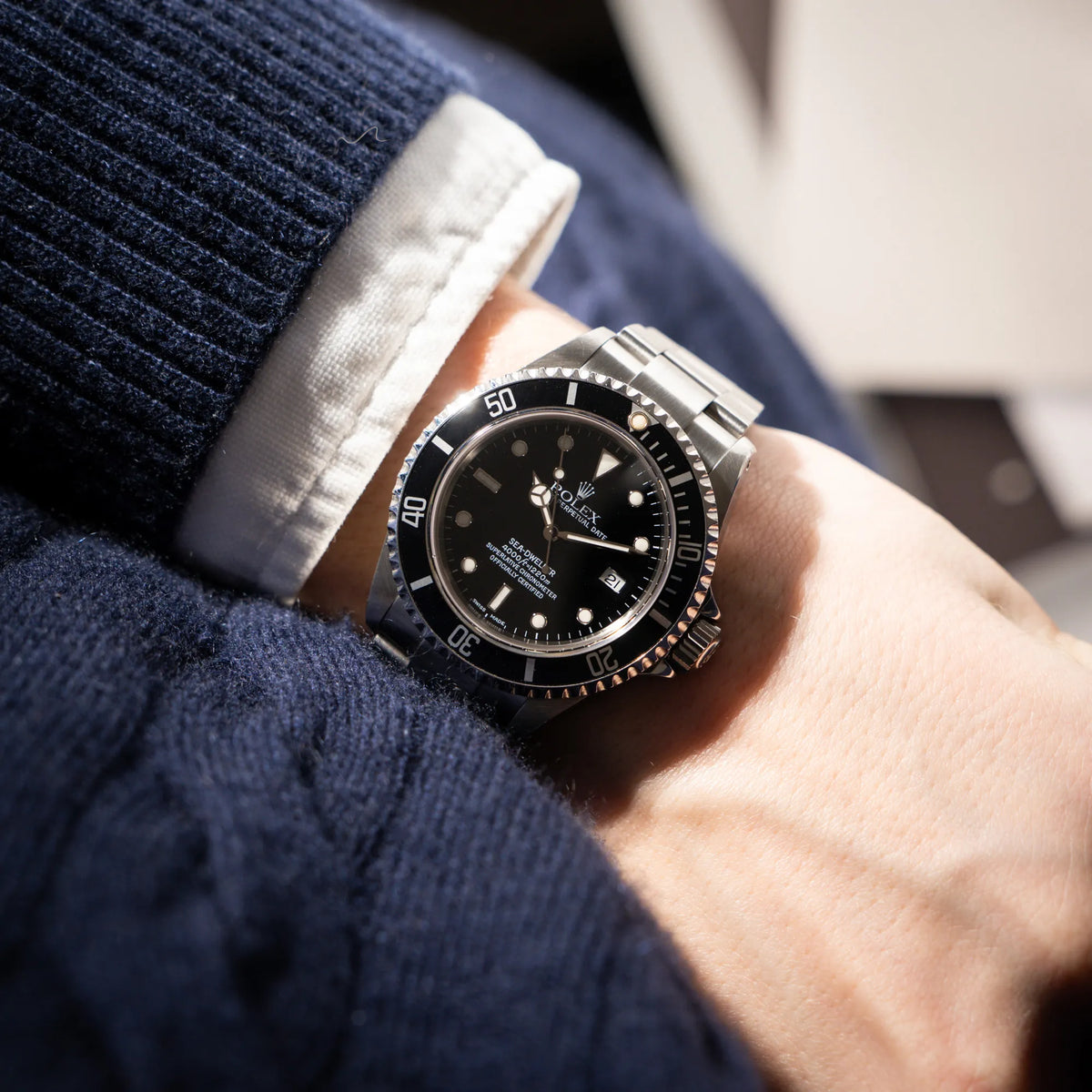 Mann trägt die Rolex Sea-Dweller 4000 der Referenz 16600 mit der klassischen schwarzen Aluminium-Lünette aus Dezember 2002 an seinem Handgelenk
