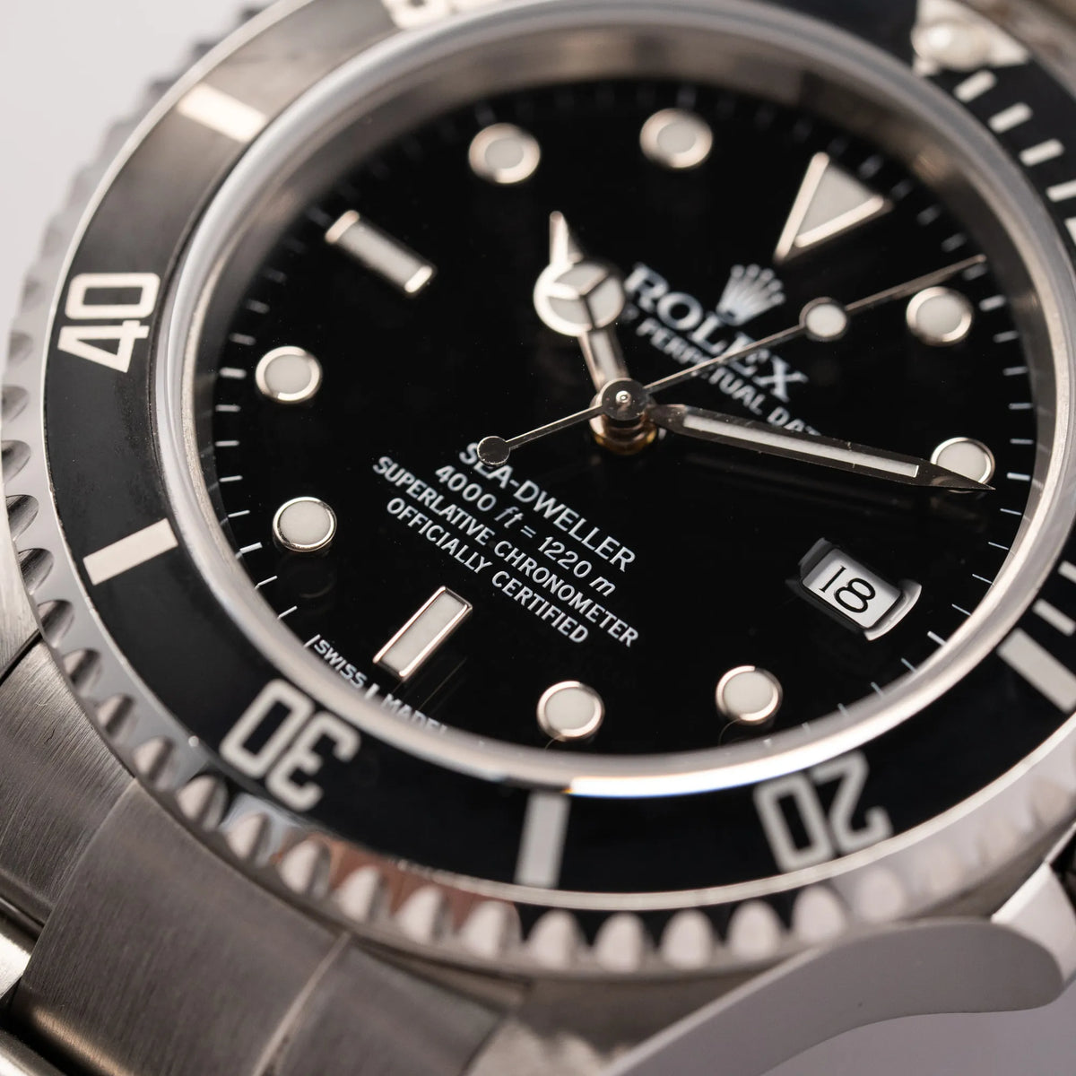 Detailaufnahme der Rolex Sea-Dweller 4000 der Referenz 16600 mit schwarzem Blatt und schwarzer Aluminium-Lünette mit Fokus auf dem Index bei 6 Uhr
