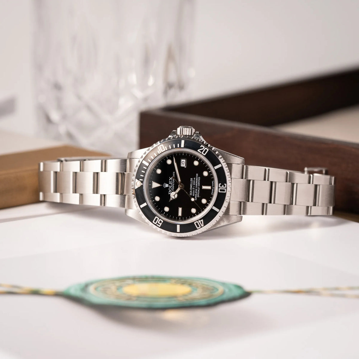 Rolex Sea-Dweller 4000 der Referenz 16600 mit schwarzem Blatt und schwarzer Aluminium-Lünette liegt seitlich auf dem Gehäuse auf einem Uhrenbuch