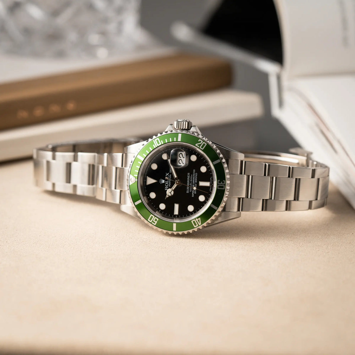Produktfotografie der Rolex Submariner Date 16610LV aus 2007 mit schwarzem Zifferblatt und der grünen "Kermit" Aluminium-Lünetten-Einlage, während die Uhr auf einem Juwelierstablet liegt