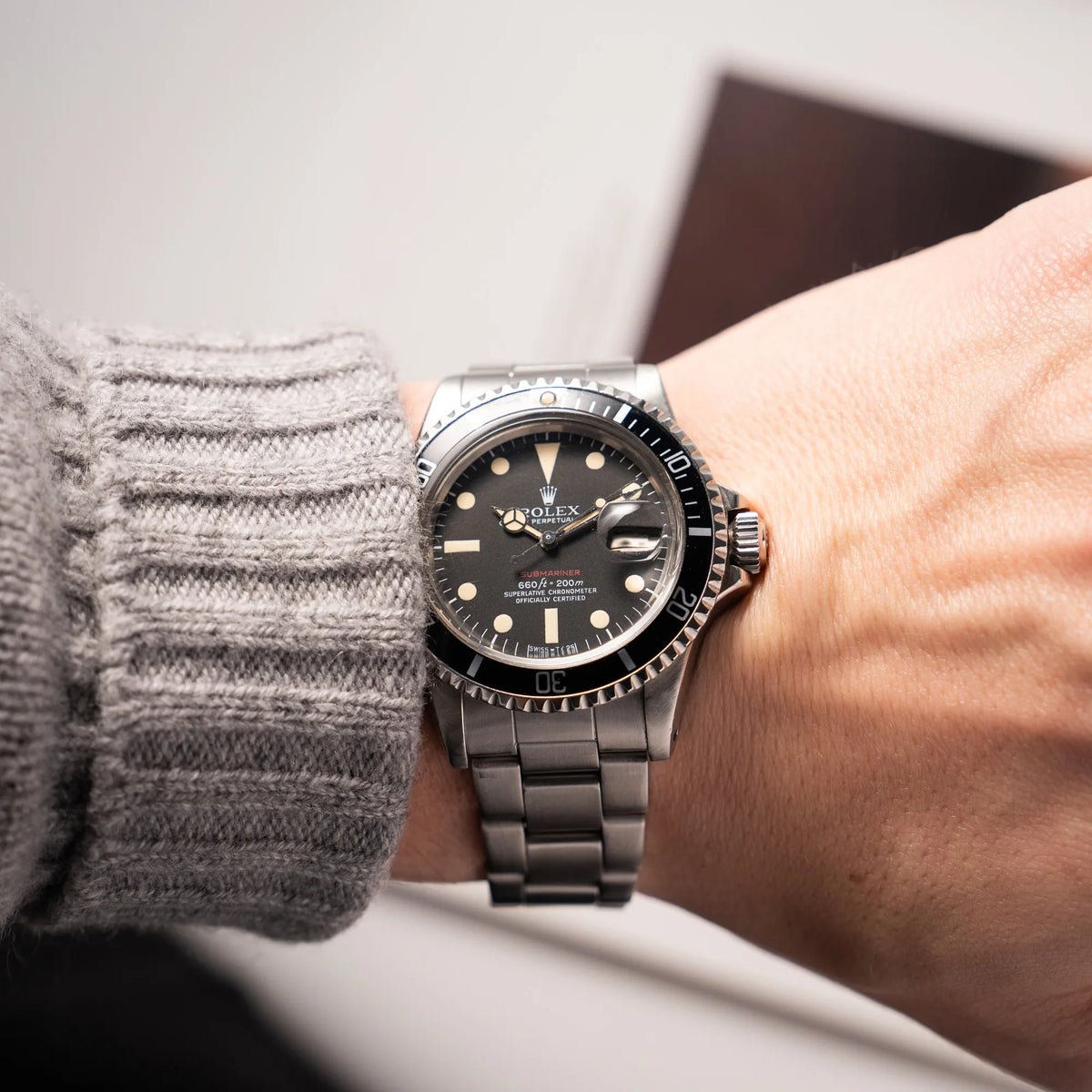 Mann trägt die Rolex Submariner Date 1680 mit dem Submariner Red Schriftzug auf dem Mark V Zifferblatt mit schöner gleichmäßiger Patina bei den Zeigern und Indizes an seinem Handgelenk