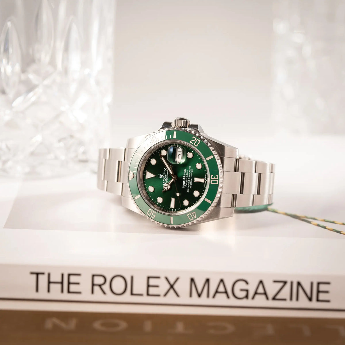 Rolex Submariner Date 116610LV, Nickname "HULK", mit dem grünen Zifferblatt und der grünen Keramik-Lünette, an dem klassischen Oyster-Stahl-Armband liegt auf der seitlichen Gehäuseflanke