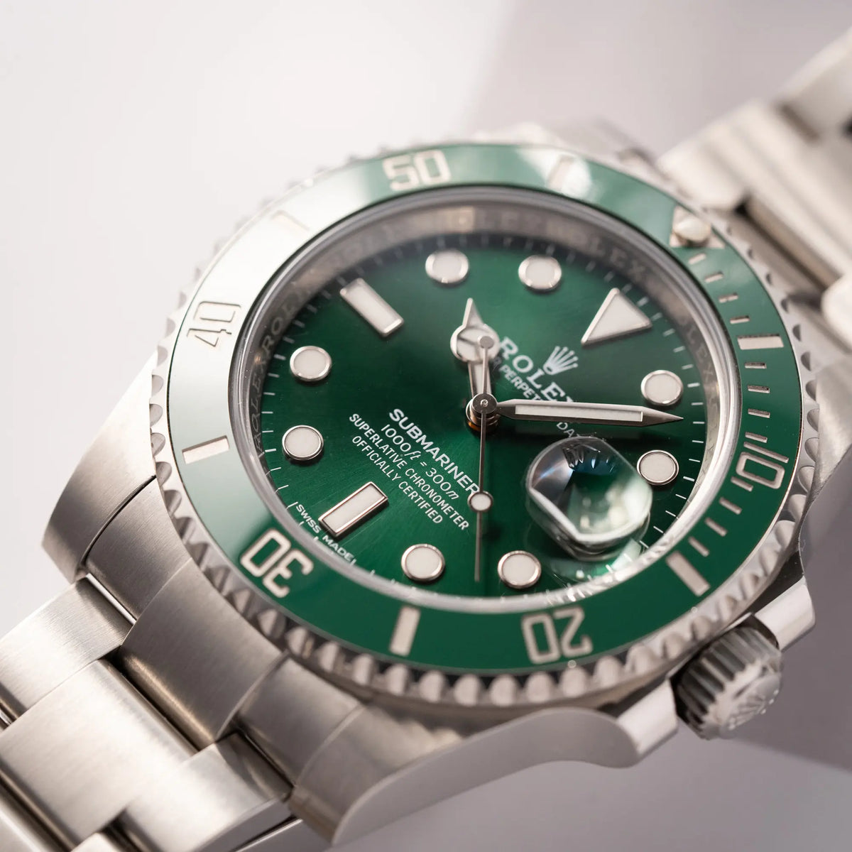 Detailaufnahme der Rolex Submariner Date 116610LV, Nickname "HULK", mit dem grünen Zifferblatt und der grünen Keramik-Lünette, an dem klassischen Oyster-Stahl-Armband mit Fokus auf dem Submariner-Schriftzug bei 6 Uhr
