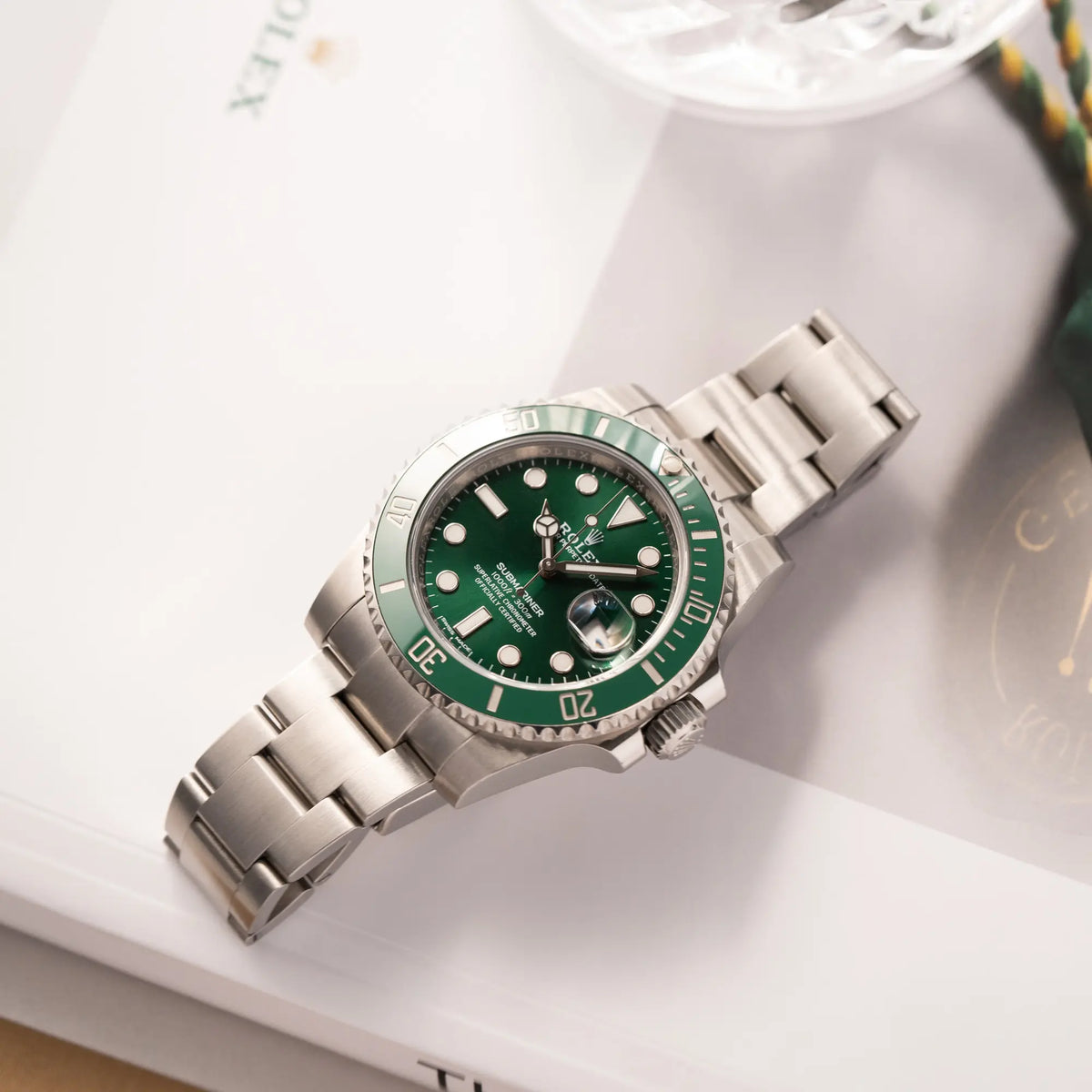Rolex Submariner Date 116610LV, Nickname "HULK", mit dem grünen Zifferblatt und der grünen Keramik-Lünette, an dem klassischen Oyster-Stahl-Armband, liegt auf einem Uhrenbuch