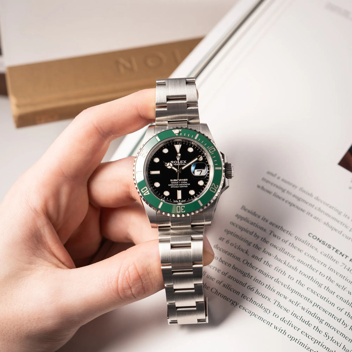 Mann hält die Rolex Submariner Date Starbucks der Referenz 126610LV im 41mm Oyster-Case mit der typischen grünen Keramik-Lünette in seiner Hand und präsentiert die Uhr in die Kamera