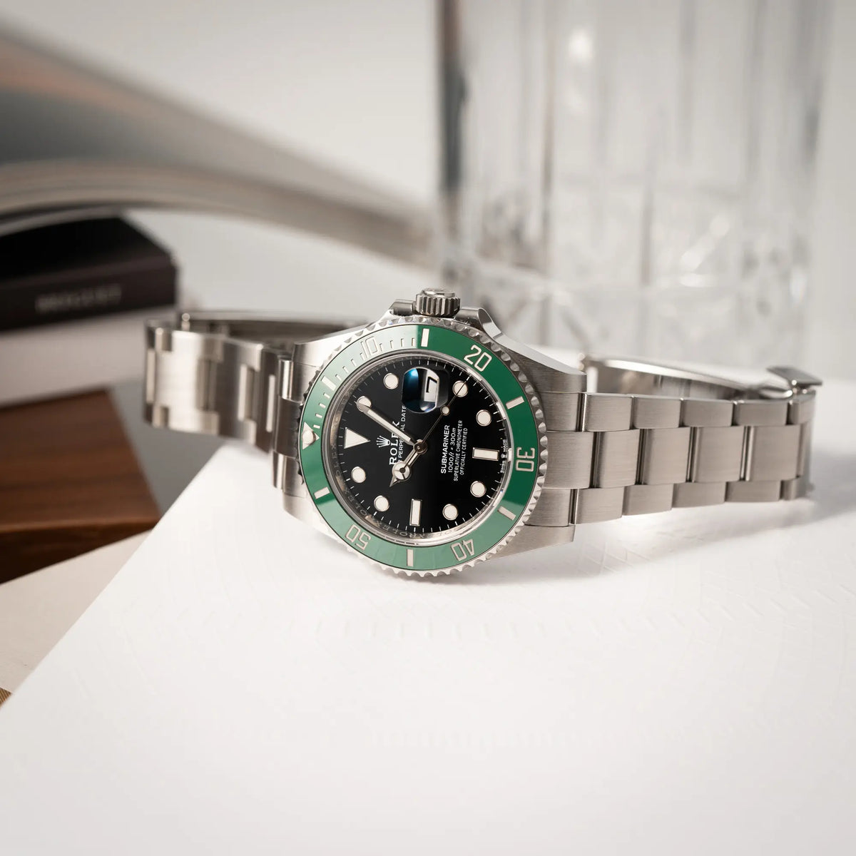 Rolex Submariner Date Starbucks der Referenz 126610LV im 41mm Oyster-Case mit der typischen grünen Keramik-Lünette liegt seitlich auf der Gehäuseflanke
