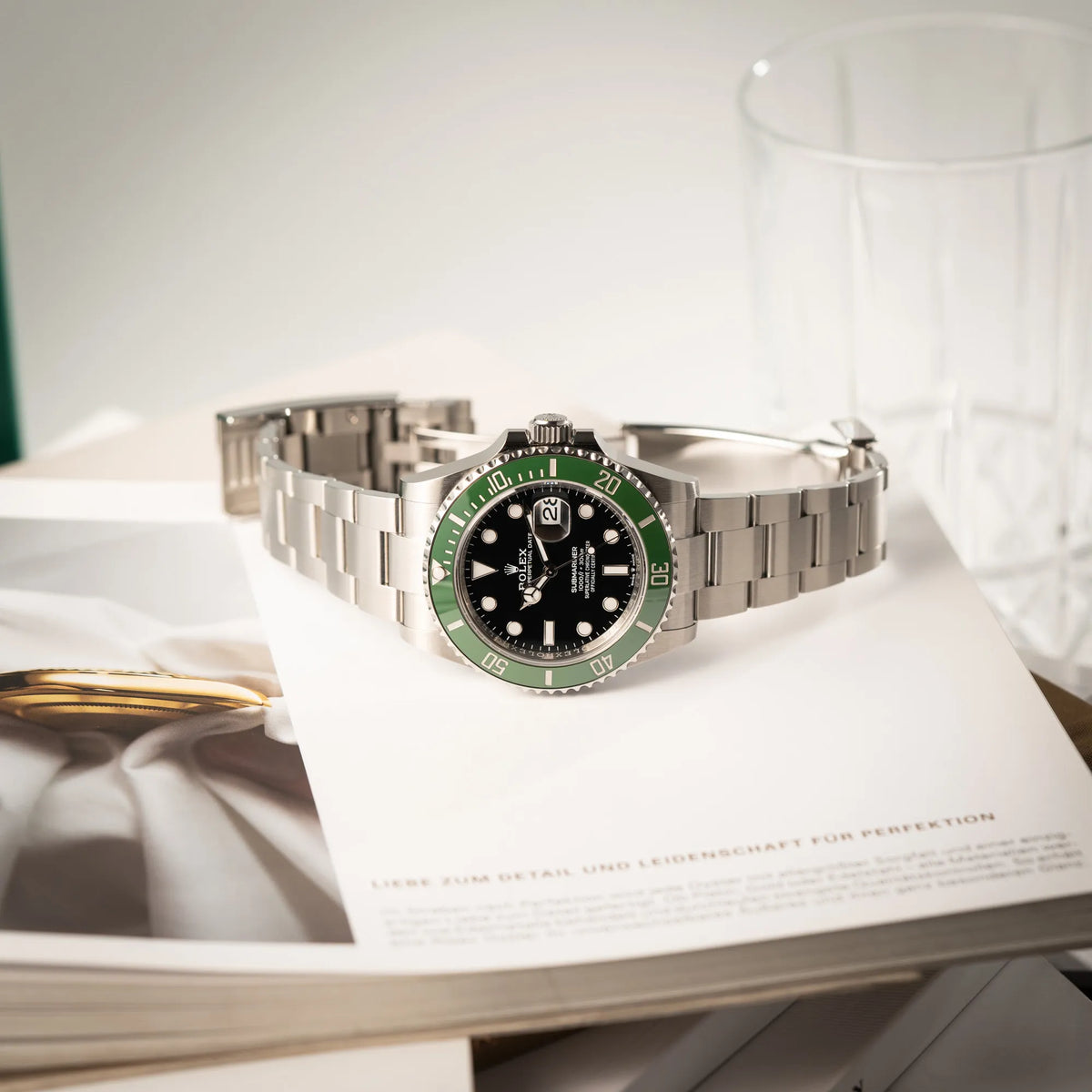 Produktfotografie der seitlich auf dem Gehäuse liegenden Rolex Submariner Date Starbucks 126610LV Mark 2 aus 2025 mit der typischen grünen Cerachrom-Lünette
