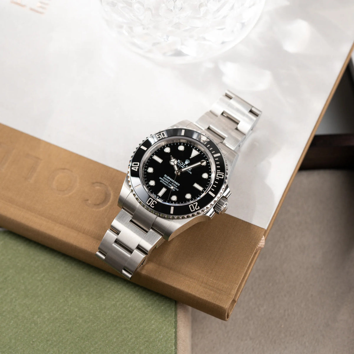 Produktfotografie der auf dem Edelstahl-Armband liegenden Rolex Submariner No Date der Referenz 124060 im 41mm-Oyster-Case mit schwarzem Zifferblatt und schwarzem Keramik-Lünetten-Inlay