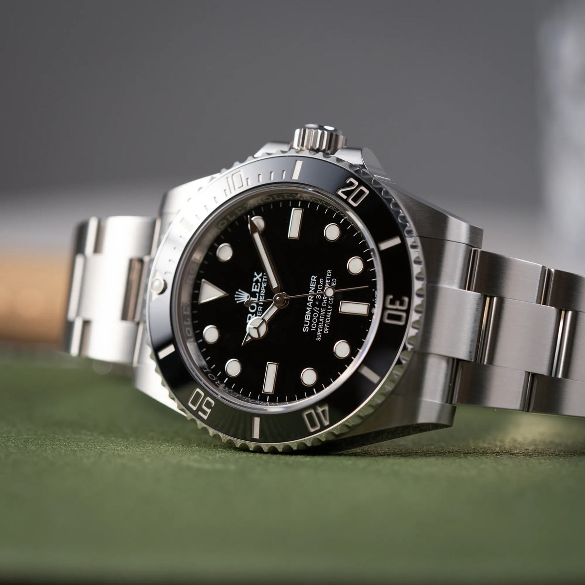 Produktfotografie der Rolex Submariner No Date der Referenz 124060 im 41mm-Oyster-Case mit schwarzem Zifferblatt und schwarzem Keramik-Lünetten-Inlay auf grünem Hintergrund