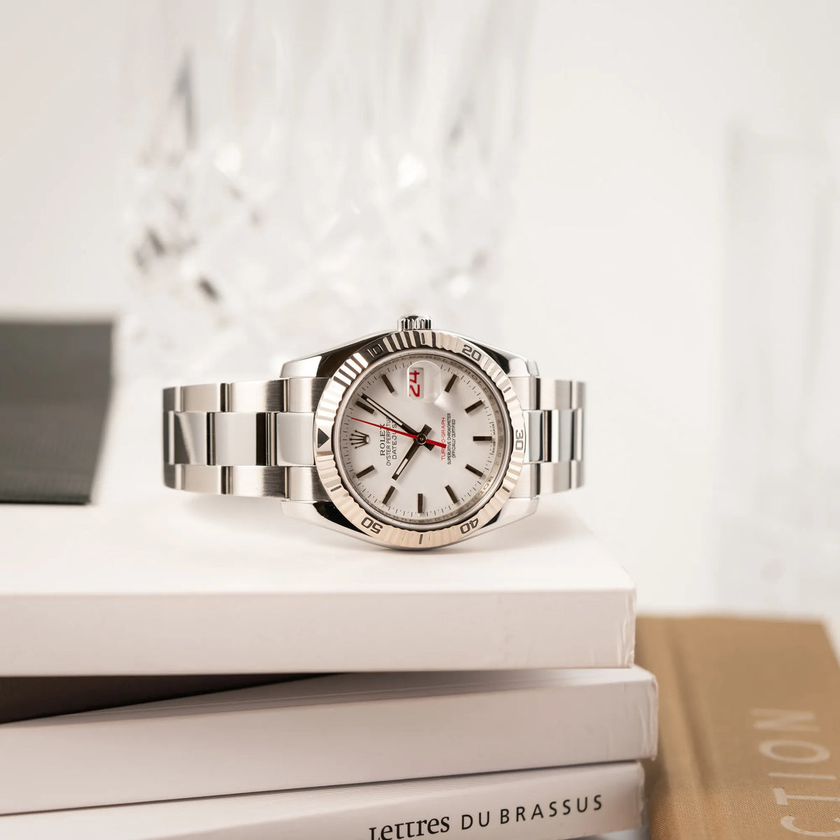 Rolex  Datejust Turn-O-Graph 116264 in 36 mm mit dem weißen Zifferblatt und dem roten Sekundenzeiger liegt auf einem Bücherstapel
