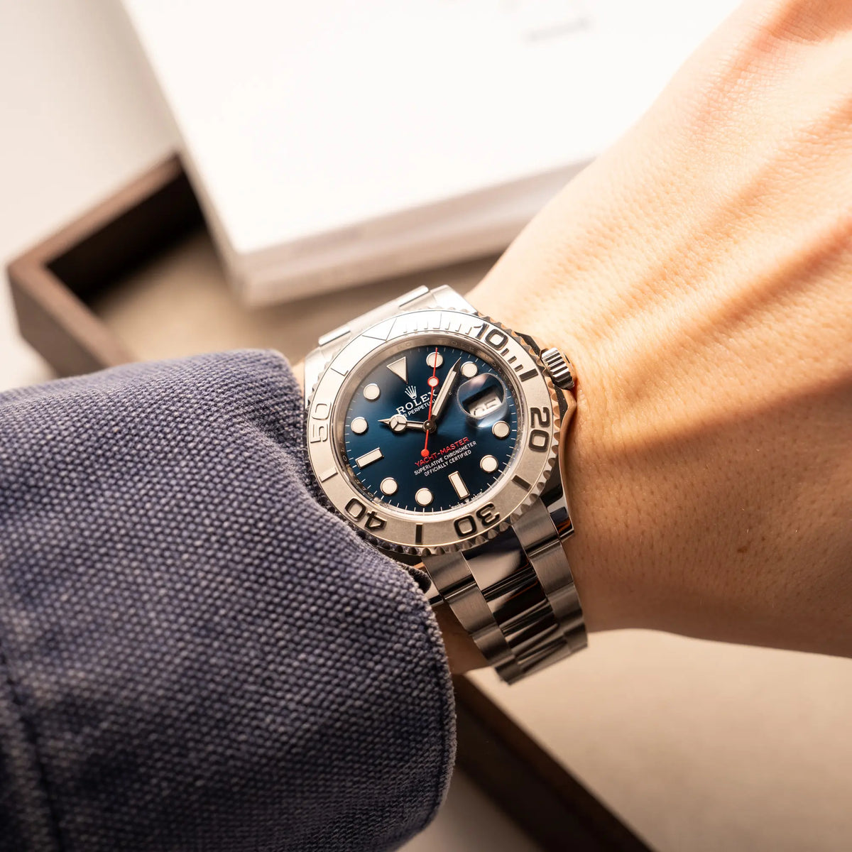 Mann trägt die Rolex Yacht-Master 40 mit blauem Zifferblatt der Referenz 126622 aus 2022 für einen Wristshot an seinem Handgelenk und präsentiert die Armbanduhr in die Kamera