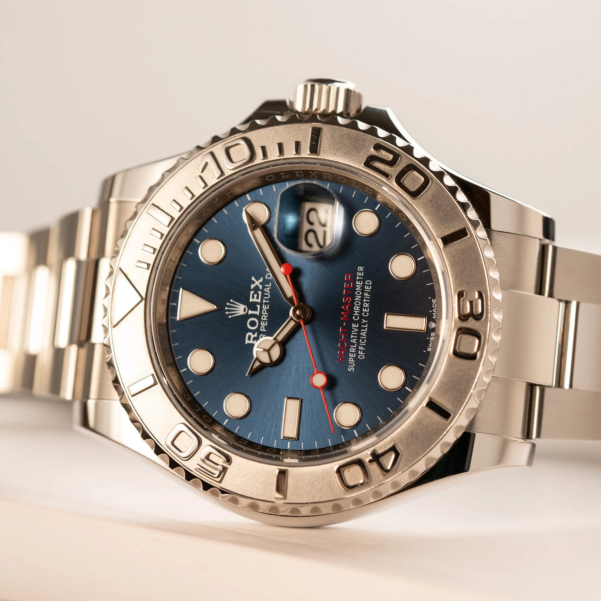 Rolex Yachtmaster 40 der Referenz 126622 mit blauem Zifferblatt und der Rolesium-Lünette aus Platin liegt seitlich auf dem Uhrengehäuse
