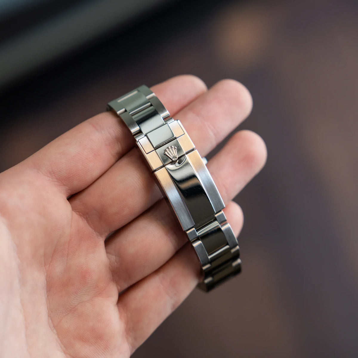 Mann hält die Rolex GMT Master 2 in Schwarz mit der Keramik-Lünette in einem neuwertigen Zustand in seiner Hand und präsentiert die Faltschliesse
