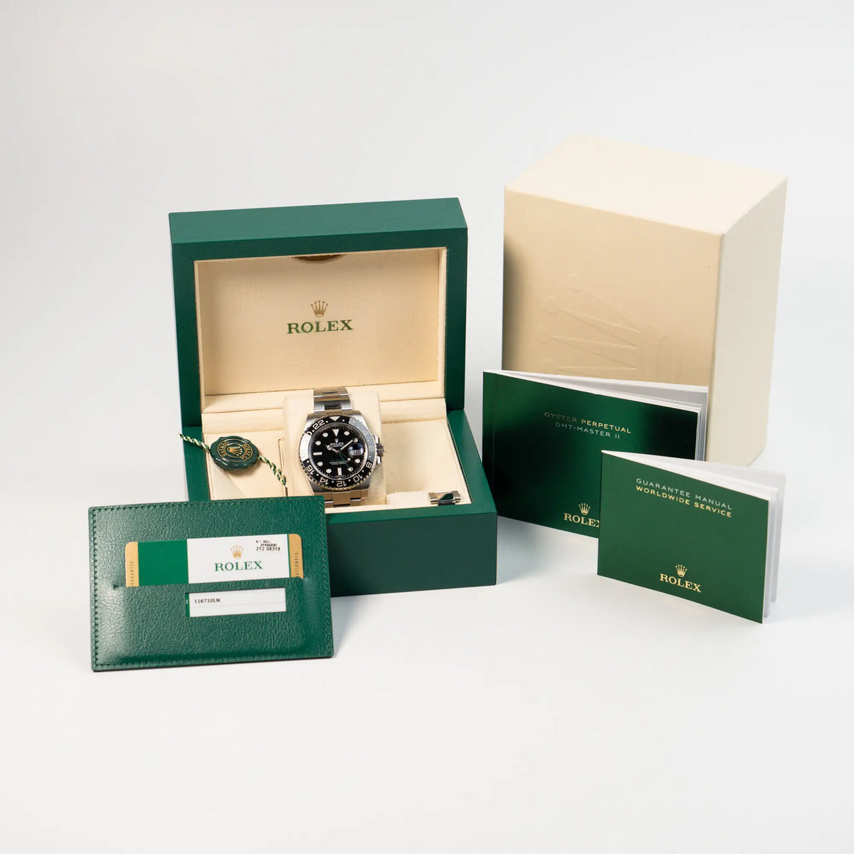 Frontale Ansicht der Rolex GMT Master 2 in Schwarz mit der Keramik-Lünette in einem neuwertigen Zustand zusammen mit dem Lieferumfang, bestehend aus Box, Papieren, Booklets und Hangtags