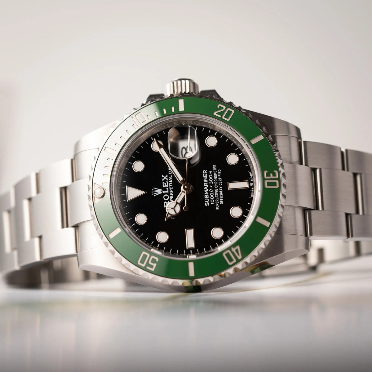Produktfotografie zeigt den Uhrenkopf der seitlich auf dem Uhrengehäuse liegenden Rolex Submariner Date Starbucks der Referenz 126610LV mit der grünen MK2-Lünette