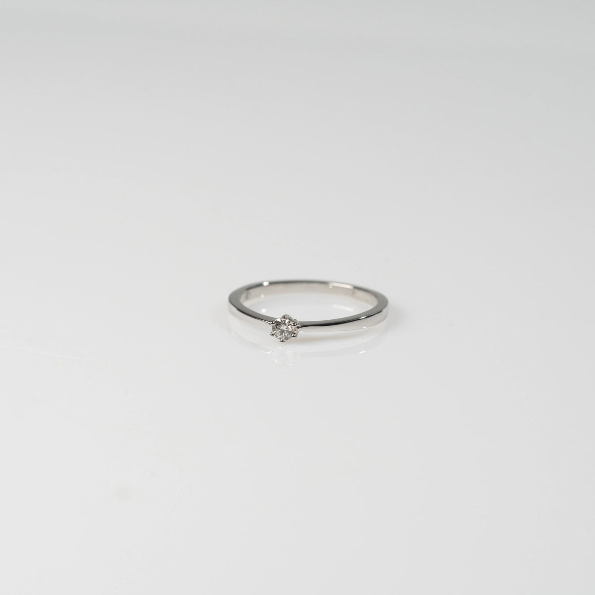Produktfotografie des liegenden Weißgold-Verlobungsrings "Promise" aus der Schmuckatelier Lang Collection mit einem in einer 6er Kappe gefassten Diamanten
