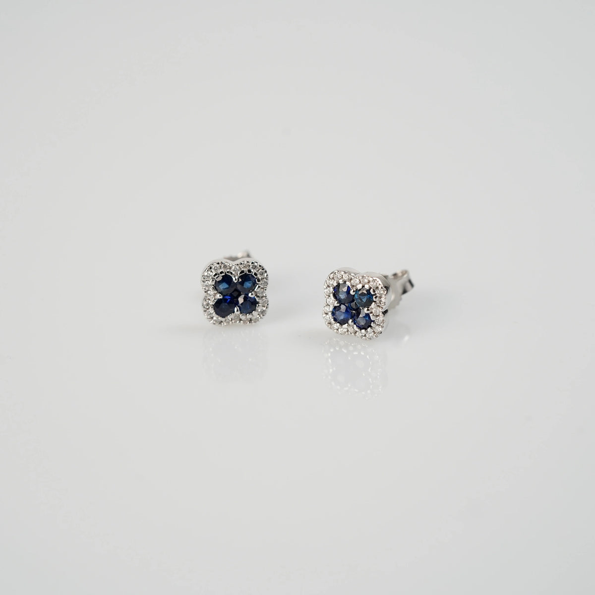 Leicht schräger Blick auf die Ohrstecker aus der Schmuckatelier Lang Collection in einer Kleeblatt-Form, bei dem die Saphire durch die kleinen Diamanten umrandet sind
