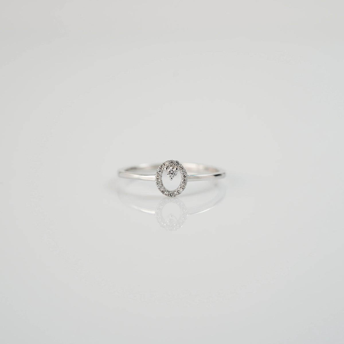 Produktfotografie des liegenden "Fine Oval" Verlobungsrings aus Weißgold, der mit einem ovalen Diamantkranz verziert wurde