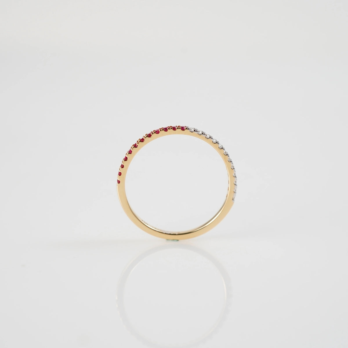 Seitliche Ansicht des liegenden Memoire Rings aus der Schmuckatelier Lang Collection, der halb mit Rubinen und halb mit Diamanten besetzt ist