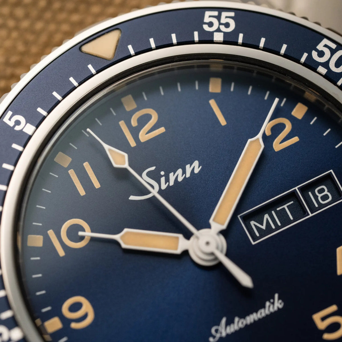 Detailaufnahme der der Taucheruhr Sinn Automatik SA in Blau mit beigen Akzenten am Textilband mit Fokus auf dem Zeigersatz