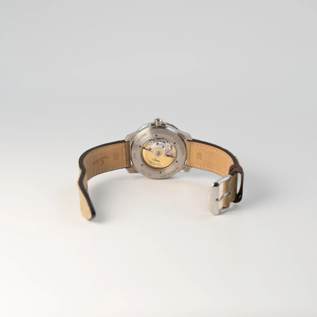 Blick auf den gläsernen Gehäuseboden und die geöffnete Dornschliesse der  Sinn Automatik SA Taucheruhr in Blau mit beigen Akzenten am Textilband