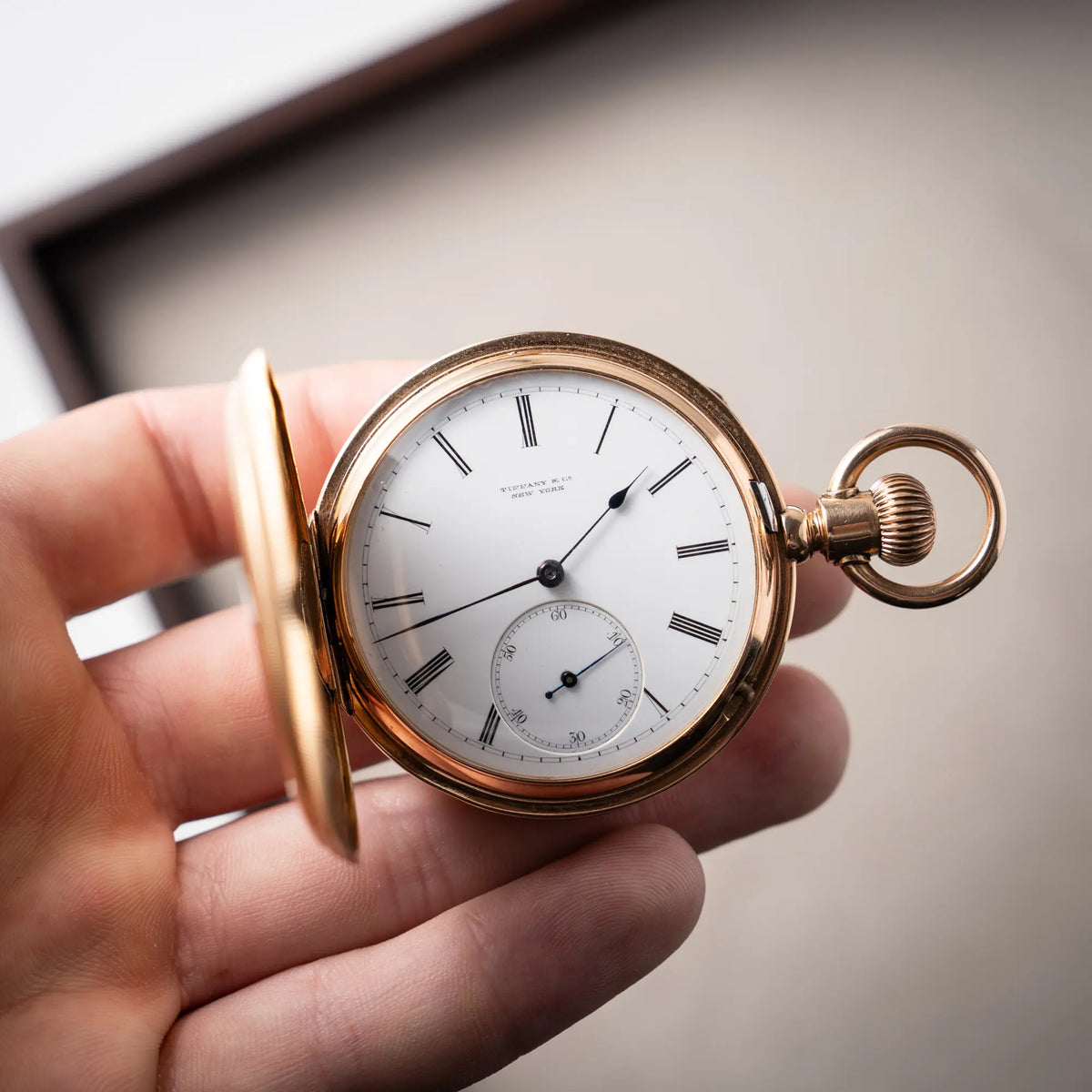 Mann präsentiert die Tiffany & Co Savonette Taschenuhr aus 18k Gelbgold mit weißem Zifferblatt und römischen Indizes
